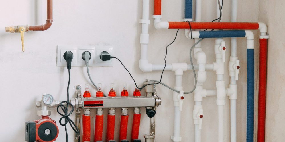 Detailed view of an intricate heating system setup featuring red and blue color-coded pipes, valves, and gauges. Connection diagram of a gas boiler with a underfloor heating system.